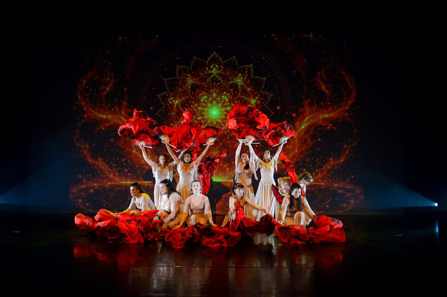 Ensemble de danseuses agitant de longs voiles rouges sous les projecteurs